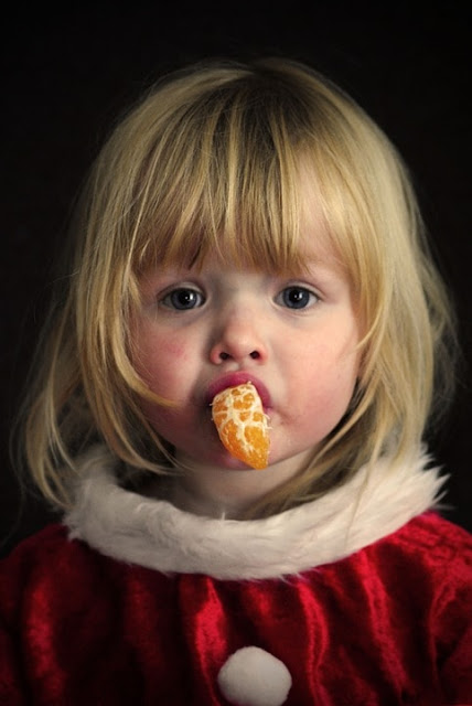 طفلة شقراء تأكل برتقال