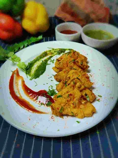 Serving paneer pakora with green chutney and tomato ketchup in a garnished plate