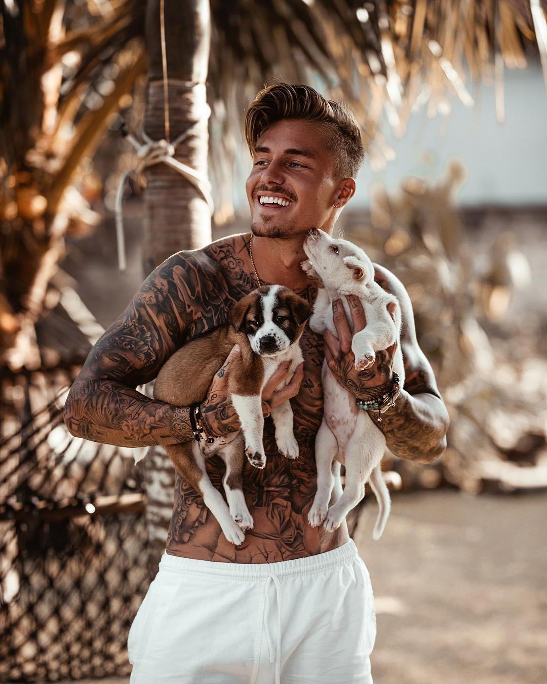 adorable-fit-tattoo-body-dude-smiling-playing-with-small-cute-dog-puppies