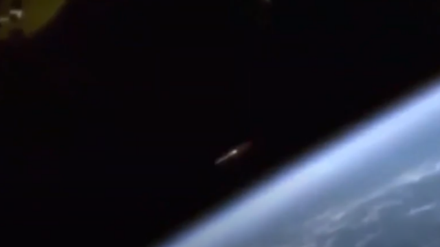We see here a silver metallic UFO flying past the ISS camera.