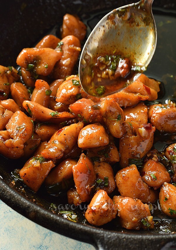 You will love this quick,best and easy Honey Butter Garlic Chicken bites which are so tender and juicy also cooked in delicious honey butter garlic sauce which is so easy to make and enjoy with rice and steamed vegetables. #savorybitesrecipes #honeybuttergarlicchicken #appetizer #chicken #easydinner #dinnerrecipes #honeybutterchicken a close up of a spoon dropping honey butter garlic sauce on chicken in a pan
