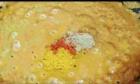 Adding red chilli powder, turmeric powder, Garam masala in gravy for matar paneer