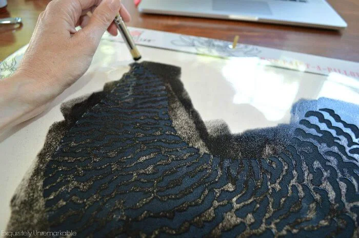 Using a paint brush to add paint to a pillow stencil