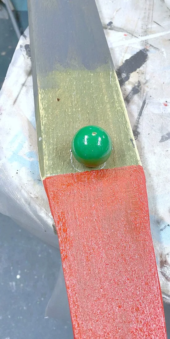 painted board with a wooden ball for a nose