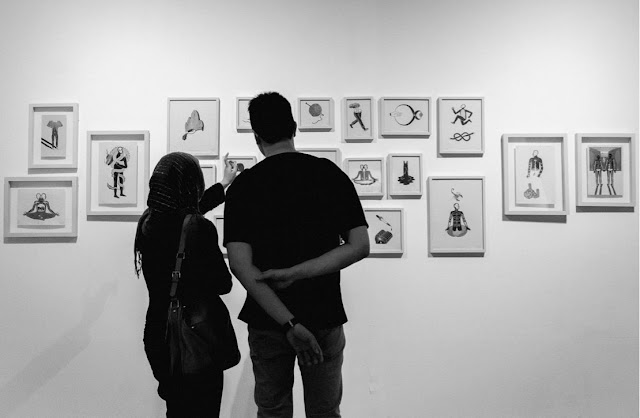 A couple looking and discussing some art prints on display.