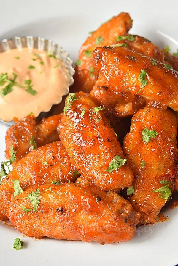 Honey hot wings on a white plate with dip