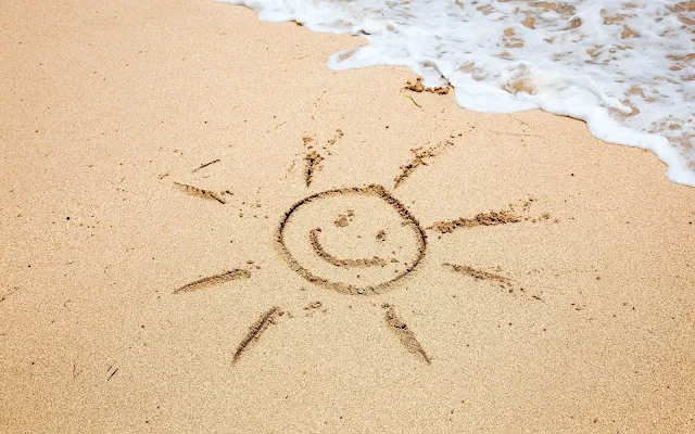 Tekening van een zon in het zand op het strand