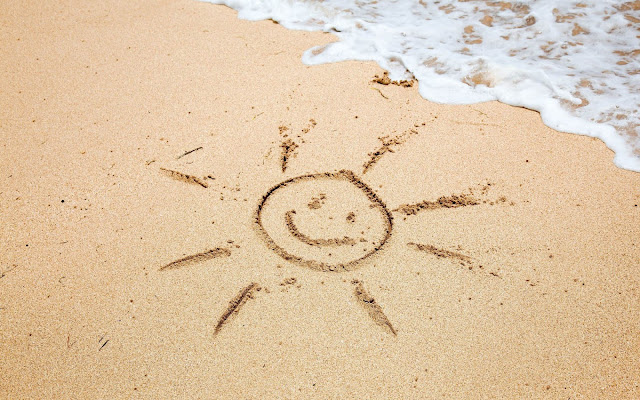 Tekening van een zon in het zand op het strand