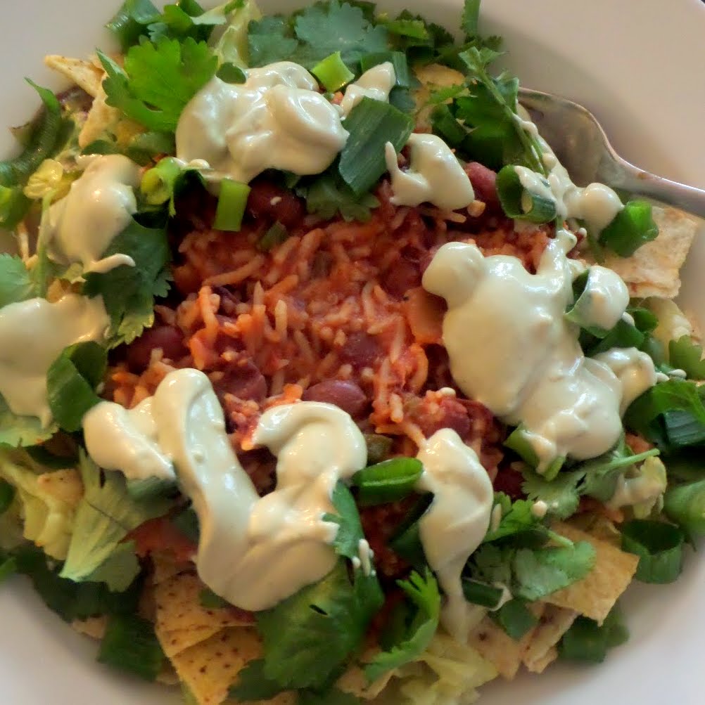 Bean and Rice Taco Salad:  A vegetarian meal of tortilla chips and lettuce, topped with spicy rice and beans, and finished with avocado sour cream and cilantro.