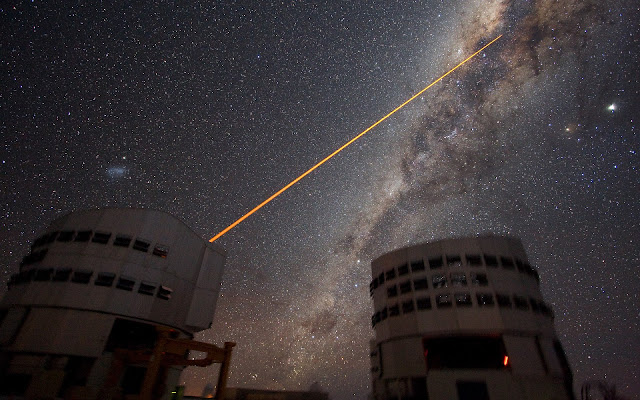 Shooting a Laser at the Galactic Centre The sky above Paranal on 21 July 2007. Two 8.2-m telescopes of ESO's VLT are seen against the wonderful backdrop of the myriad of stars and dust that makes the Milky Way. Just above Yepun, Unit Telescope number 4, the Small Magellanic Cloud - a satellite galaxy of the Milky Way - is shining. A laser beam is coming out of Yepun, aiming at the Galactic Centre. It is used to obtain images that are free from the blurring effect of the atmosphere. On this image, the laser beam looks slightly artificial. This is a side effect due to saturation caused by the long exposure time. Planet Jupiter is seen as the brightest object on the upper right, next to the star Antares. Image taken by ESO astronomer Yuri Beletsky.  Image Credit: ESO/Yuri Beletsky Explanation from: http://www.eso.org/public/images/eso0733b/