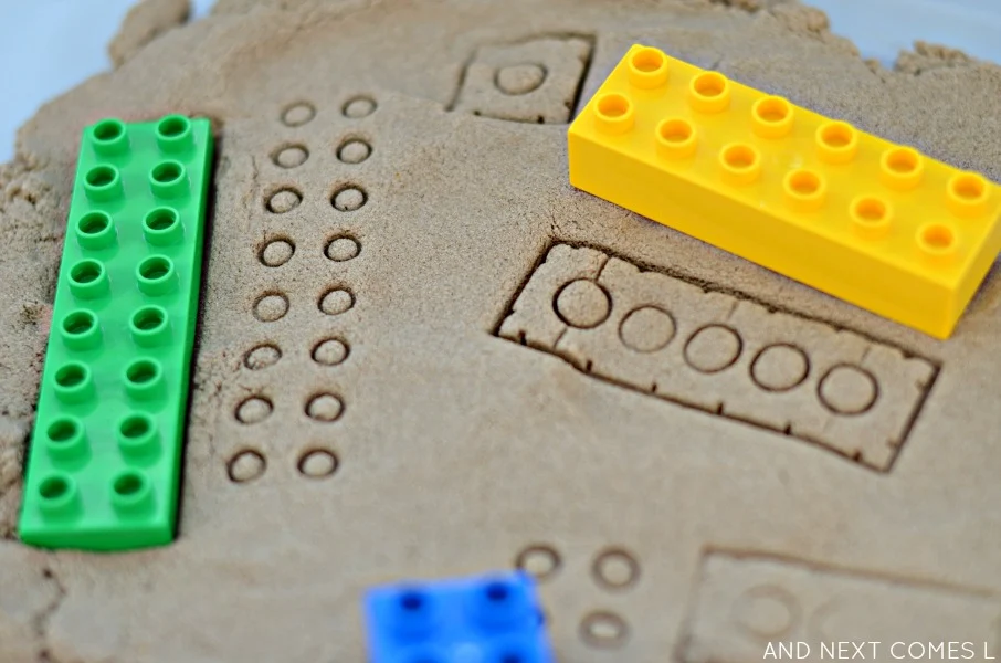 Stamping LEGO in kinetic sand activity for kids