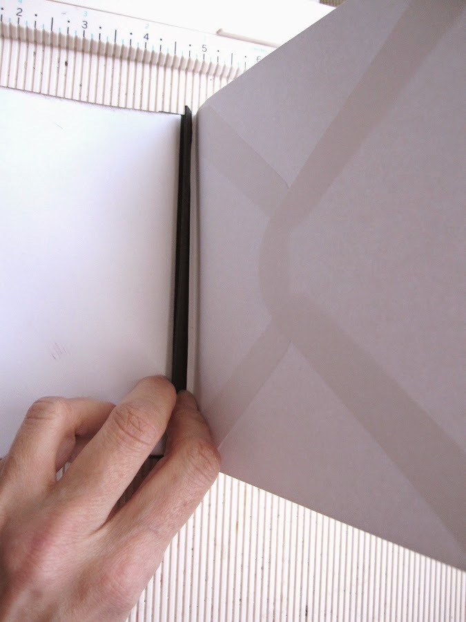 paso 8 tutorial mini-álbum scrapbook, demostración de cómo se pega el sobre al lomo por el pliegue de 1/8