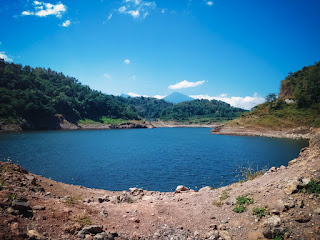 Natural Lake Water Of Titab Ularan Dam Between The Hills With Ground Rock Fragments On A Sunny Day North Bali Indonesia