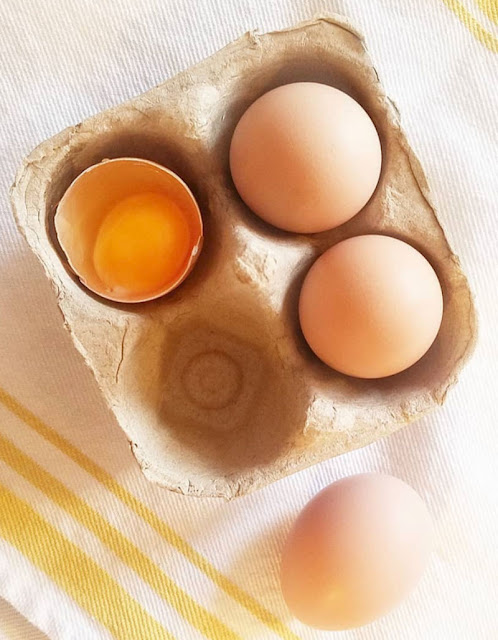 eggs in cardboard carton, one egg cracked