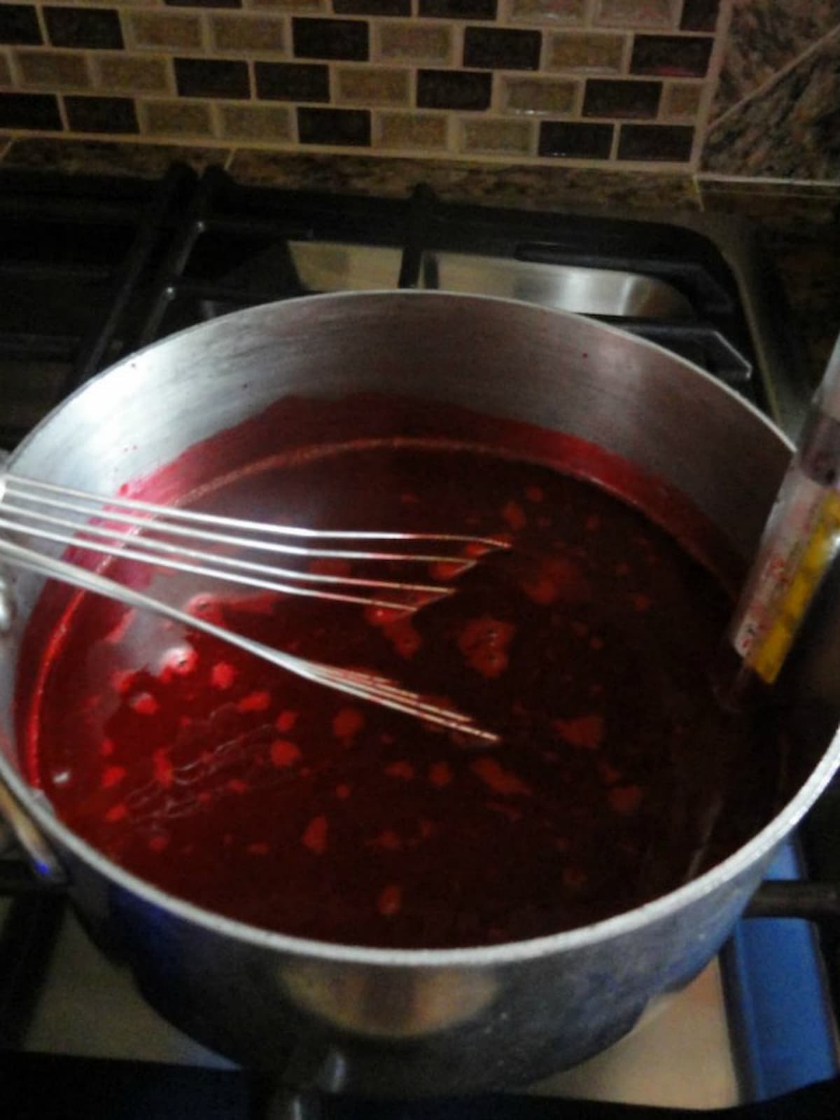 Water, Sugar, Light Corn Syrup, and Food Coloring in a large pan with a candy thermometer attached to the edge of pan.