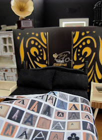 Modern black dolls' house miniature bed set in a room set up in dark shades of black, brown and cream.