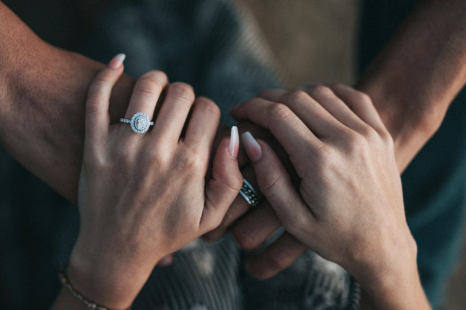 a close-up of man's and women's hands, a man put an engagement ring on her finger