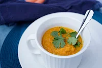 Bowl of carrot soup with cilantro on top.