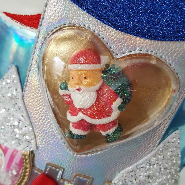close up of heart shaped clear case on side of boot with Santa figure inside
