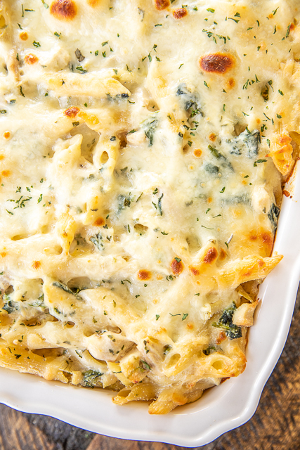 Three Cheese Chicken Spinach & Artichoke Alfredo Pasta - think cheesy chicken Alfredo pasta meets spinach & artichoke dip. Two of my all-time favorites in one pan. Super easy to make. Can freeze for a quick meal later!! Penne pasta, Alfredo sauce, ricotta cheese, sour cream, garlic, parmesan cheese, frozen spinach, chopped artichokes, eggs, and chopped chicken. Use a rotisserie chicken for quick prep. Makes a ton - great for a crowd! #pasta #chicken #spinach #artichokes #casserole #freezermeal chicken pasta in casserole dish