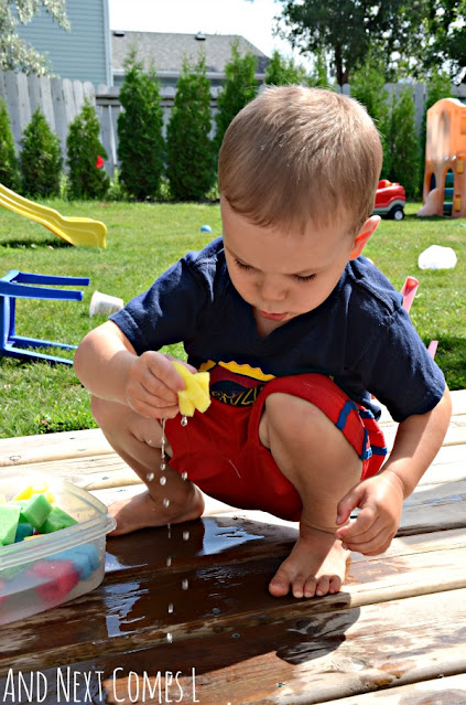 Child squeezing water out of alphabet sponges as part of a sensory play activity