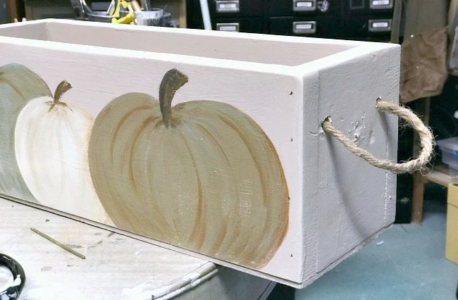 Hand painted pumpkins on a crate with a rope handle