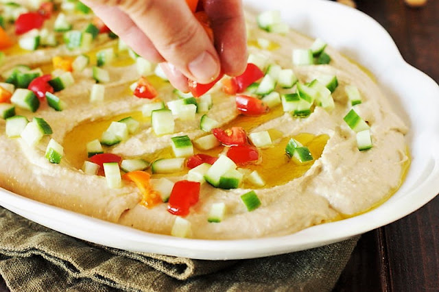 Adding Toppings to Loaded Hummus Dip Image