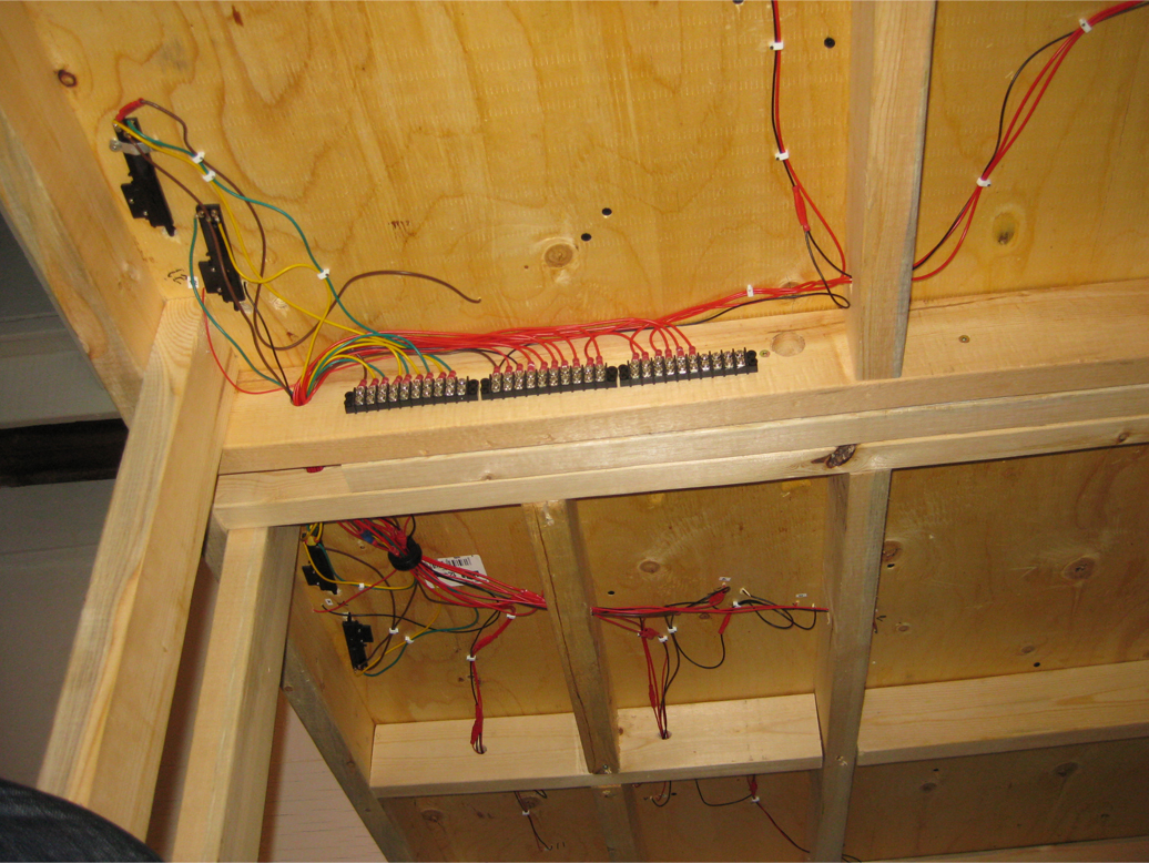 3 terminal strips installed in a row to a support beam under wooden benchwork with wire leads attached to one side