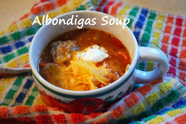 A bowl of albondigas (meatball) soup set on a colorful dish towel