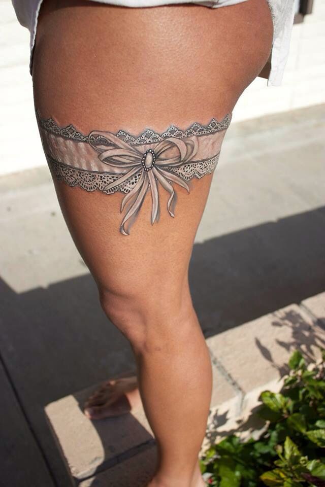 prcioso tatuaje en la pierna de un liguero de color blanco