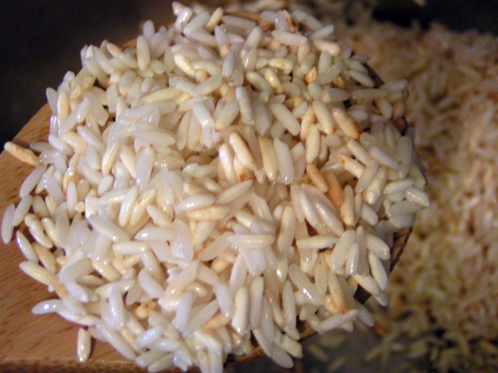 Dry rice grains being toasted in melted butter in a saucepan.