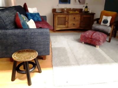 1/12 scale modern miniature lounge scene with a denim sofa and a stool next to it with the top made from an old New Zealand penny.