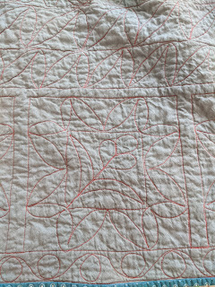 The FMQ quilting designs in red thread show up better on the grey quilt back