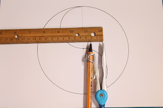 this image contains a compass and a wooden ruler placed on an A4 paper on which is drawn a yin yang symbol