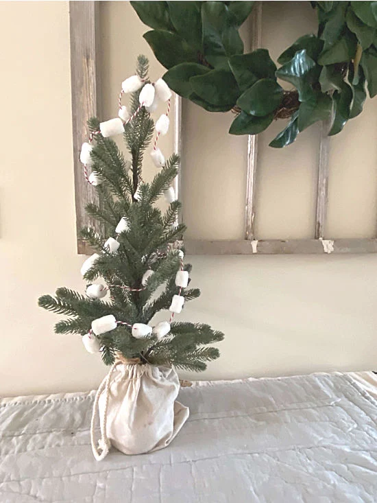 small tree in front of chippy window with wreath