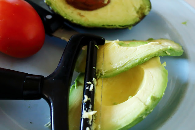 An image demonstrating the use of a block cheese slicer for fresh avocados