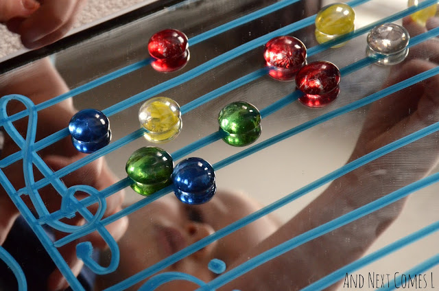 Grand staff drawn on a mirror with colored glass stones used for music notes
