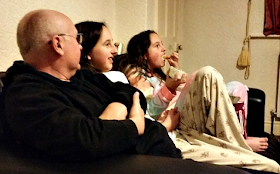 My family sat on the sofa snacking. My fella and two girls.