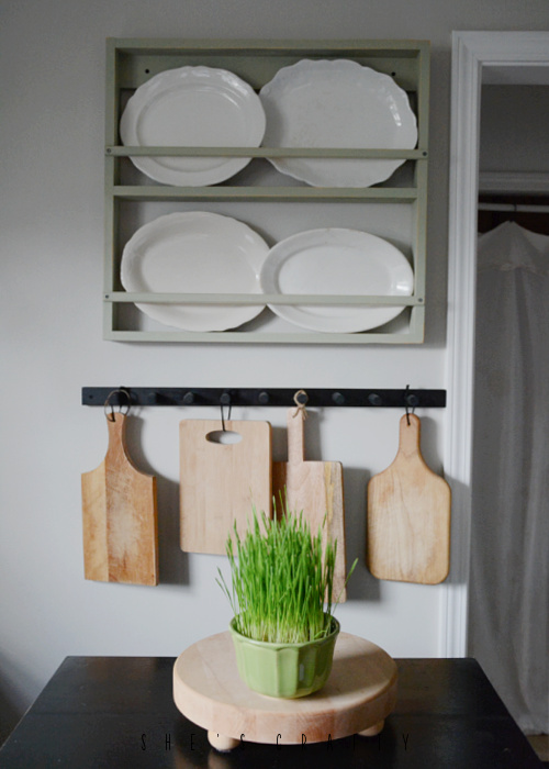 Thrifted Platters on a dish rack and thrifted cutting boards on a peg board.