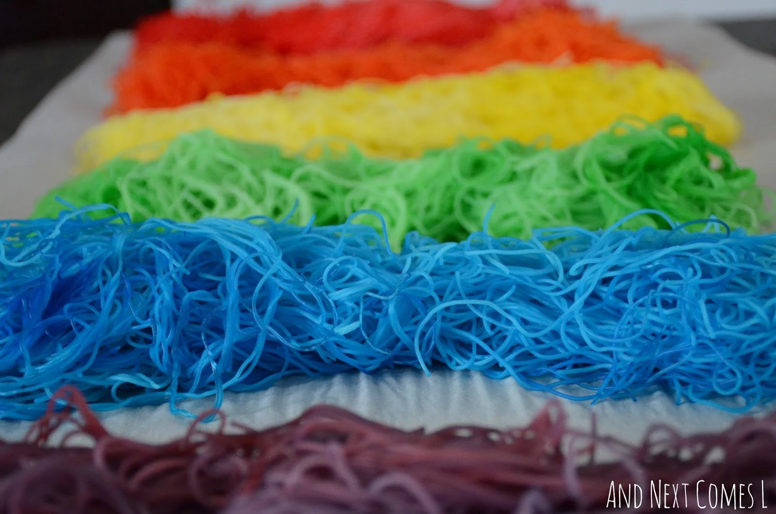 Close up of rainbow dyed rice noodles for sensory play from And Next Comes L