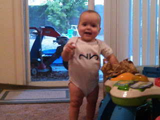 twin baby girl standing up by musical table toy wearing my twins are cuter onesie