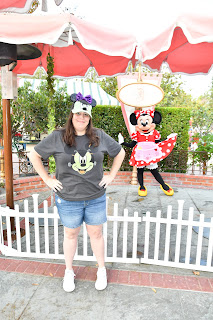 Lady with halloween shirt standing next to Minnie Mouse