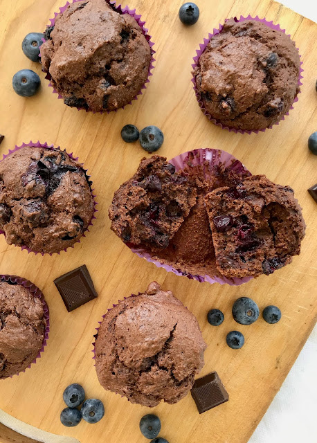 Double chocolate blueberry muffins with one split in half.