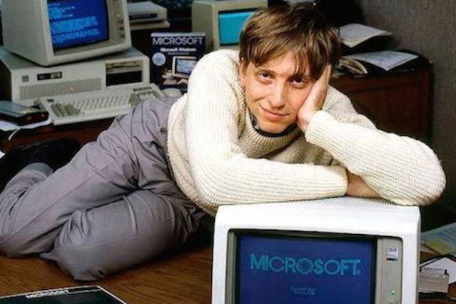 Bill Gates masasının üstünde bilgisayara yaslanmış