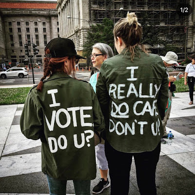 Image of two women with I vote do you painted on their t-shirts standing on City Street