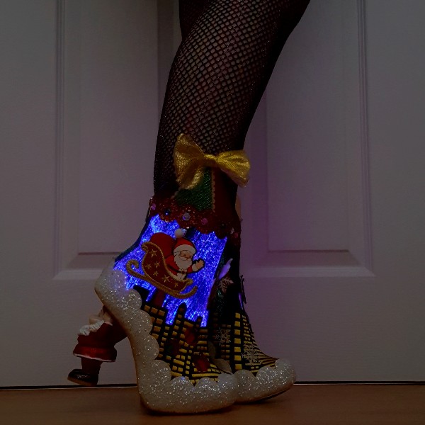 light up Christmas ankle boots being worn in the dark with lit up skyline with Santa sleigh
