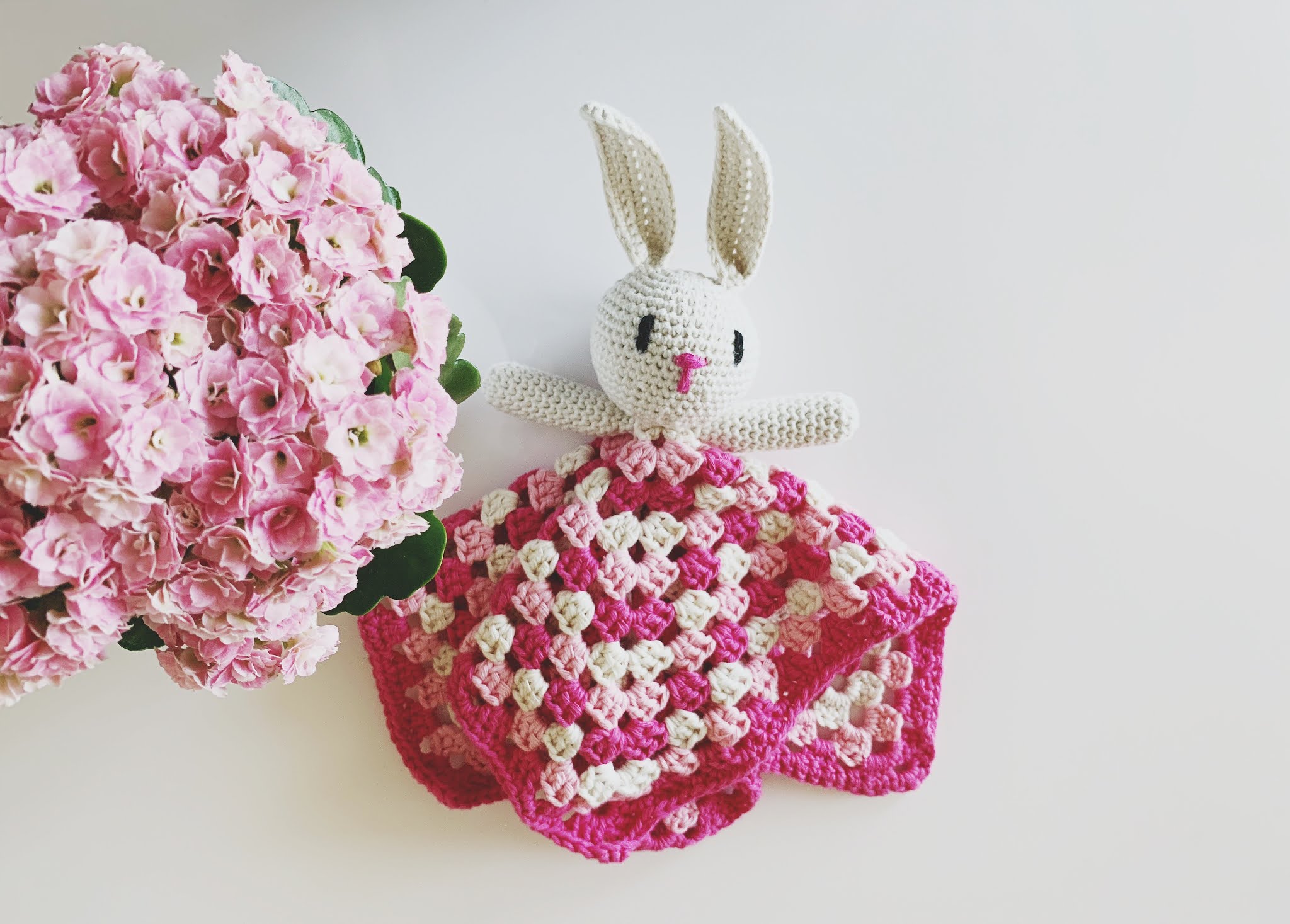 A rabbit toy made with yarn in a granny square dress