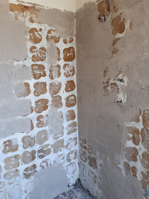 Shower wall with tiles pulled off and render, both old and new, showing.