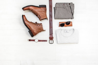 outfit of shoes, belt, watch, pants, shirt, sunglasses arranged on a white background