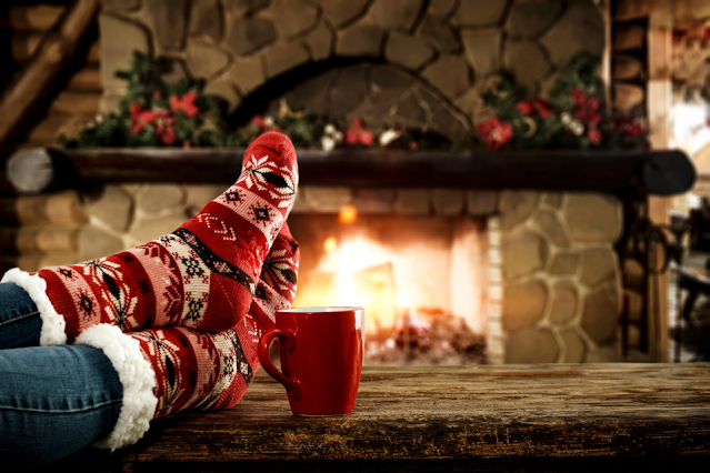 Person relaxing by a fire decorated for the holidays
